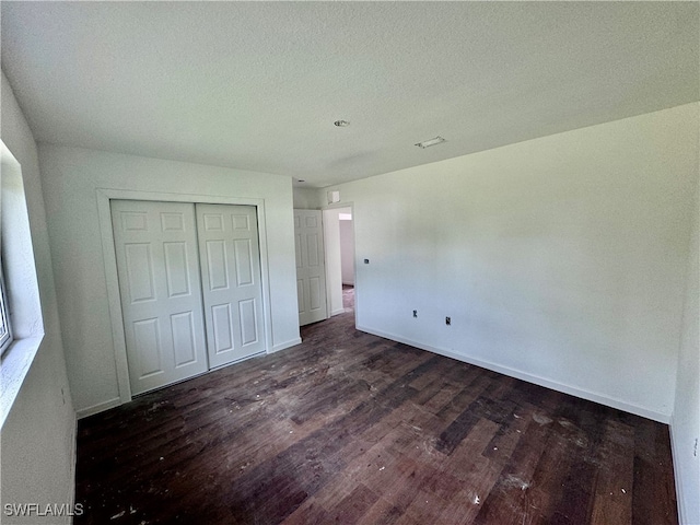 unfurnished bedroom featuring a textured ceiling, a closet, and dark hardwood / wood-style floors