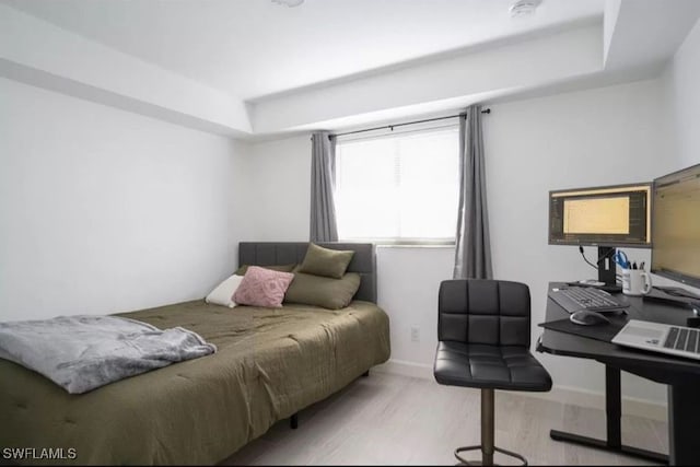 bedroom with a tray ceiling and light hardwood / wood-style floors