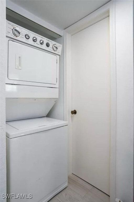 laundry room with stacked washing maching and dryer and light wood-type flooring