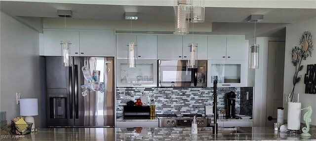 kitchen featuring backsplash, hanging light fixtures, white cabinets, and stainless steel appliances