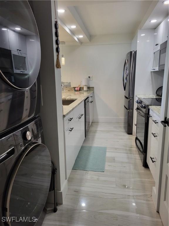450 S Gulfview Blvd Unit 505, Clearwater, FL 33767 - kitchen featuring black range oven, freestanding refrigerator, stacked washer / drying machine, white cabinets, and modern cabinets