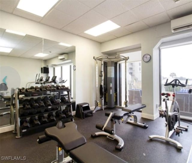 workout area featuring a wall mounted AC and a drop ceiling