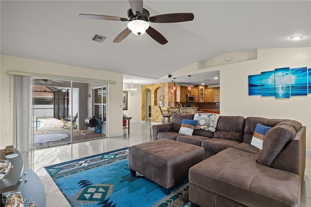 living room featuring ceiling fan with notable chandelier and vaulted ceiling