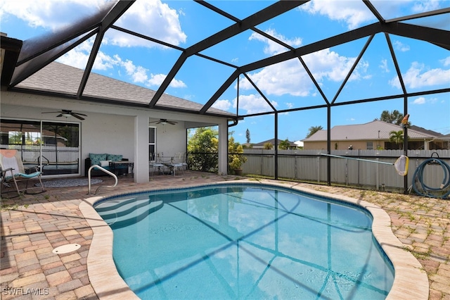 view of swimming pool featuring glass enclosure, a patio area, and ceiling fan