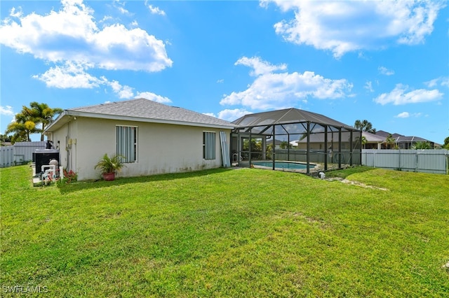 rear view of property featuring a fenced in pool, glass enclosure, and a yard