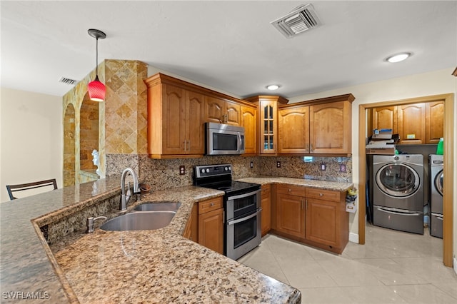 kitchen featuring stainless steel appliances, independent washer and dryer, sink, kitchen peninsula, and pendant lighting