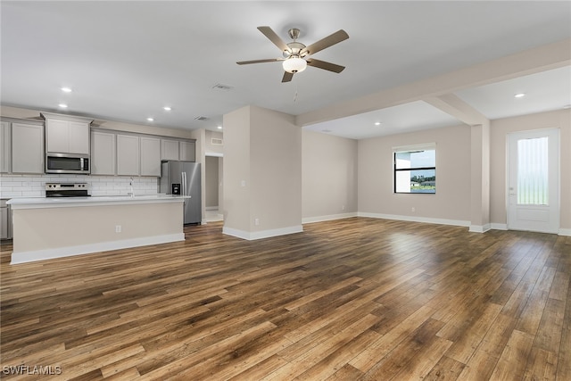 unfurnished living room with ceiling fan, wood-type flooring, and sink