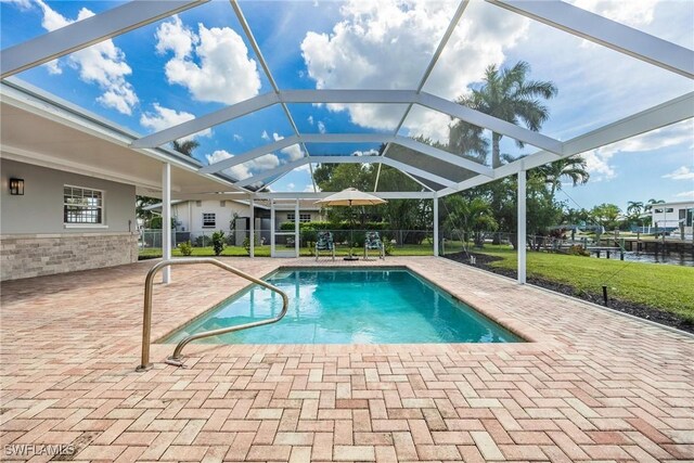 view of swimming pool featuring glass enclosure, a water view, a yard, and a patio