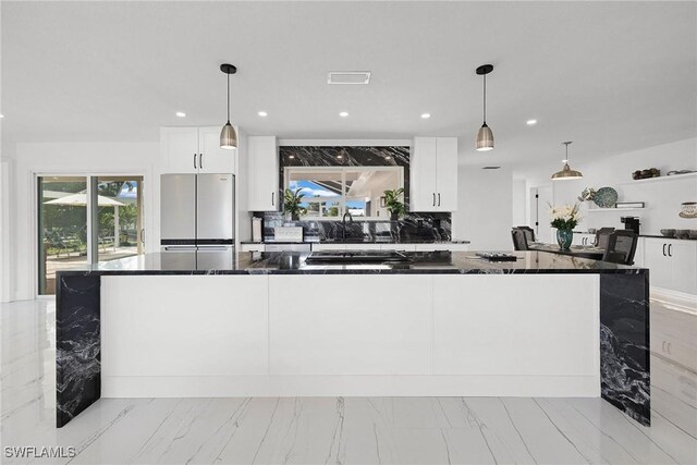 kitchen with white cabinets, appliances with stainless steel finishes, decorative backsplash, and pendant lighting