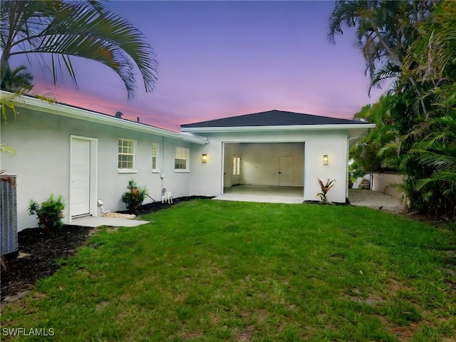 4930 Edith Esplanade, Cape Coral, FL 33904 - rear view of property featuring stucco siding, a yard, an attached garage, and a patio