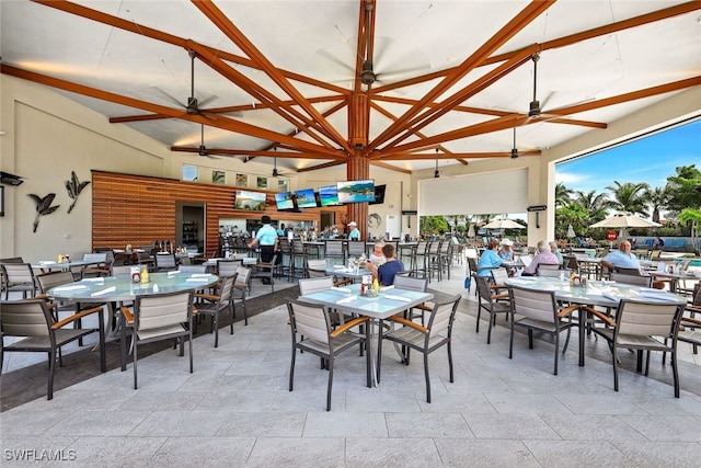 dining space with ceiling fan, high vaulted ceiling, and beam ceiling