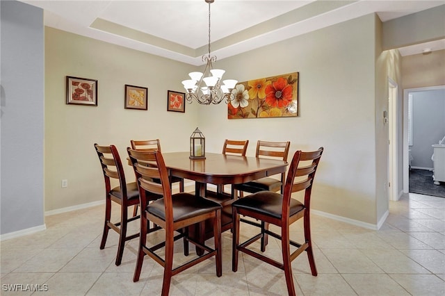 tiled dining space featuring a notable chandelier and a raised ceiling