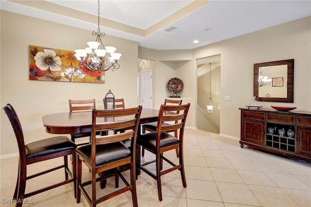 tiled dining area with a raised ceiling and a chandelier