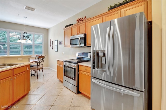 kitchen with sink, light tile patterned floors, decorative light fixtures, appliances with stainless steel finishes, and a notable chandelier