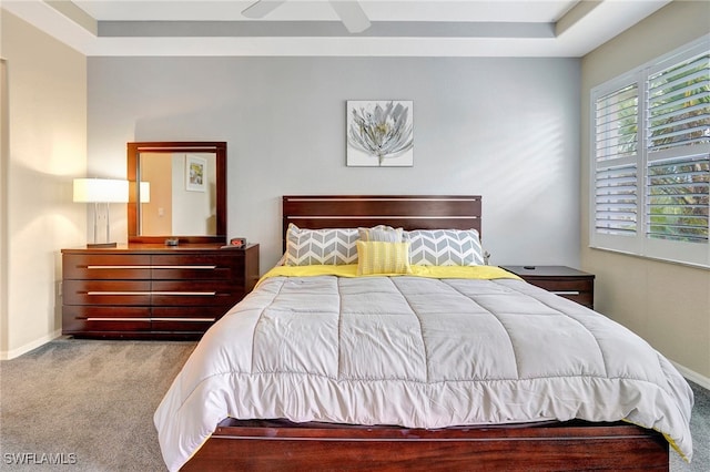 carpeted bedroom featuring ceiling fan and a raised ceiling