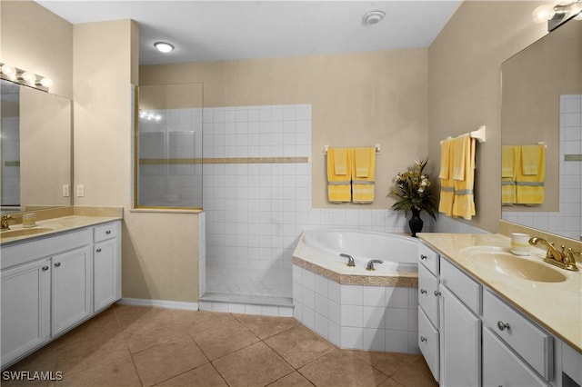 full bath featuring tile patterned flooring, two vanities, a sink, and a bath