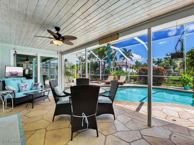 view of swimming pool with a patio area, ceiling fan, an outdoor hangout area, and glass enclosure