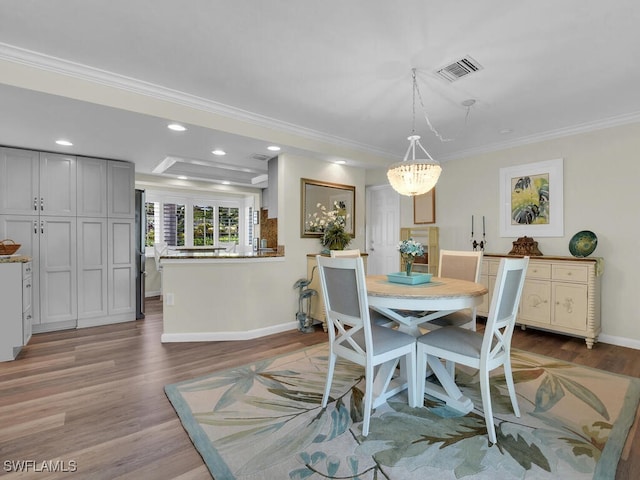 dining space featuring a notable chandelier, ornamental molding, and wood-type flooring