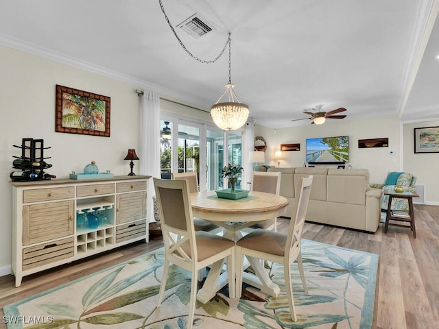 dining area with crown molding, ceiling fan with notable chandelier, and light wood-type flooring