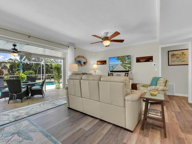 living room featuring crown molding, wood-type flooring, and ceiling fan