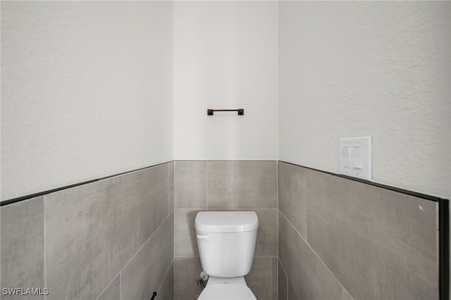 bathroom with tile walls and toilet