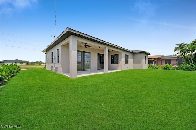 rear view of property with ceiling fan, a yard, and a patio