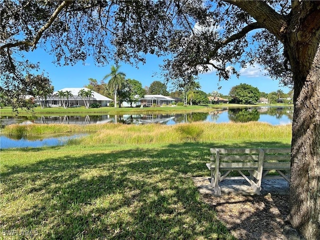 surrounding community with a water view and a yard