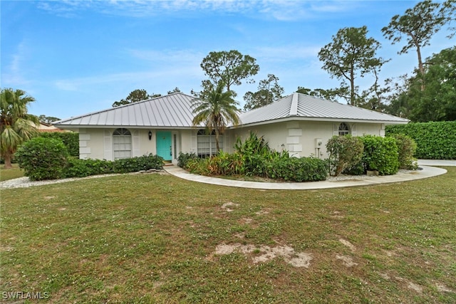 ranch-style house with metal roof, a front lawn, and stucco siding