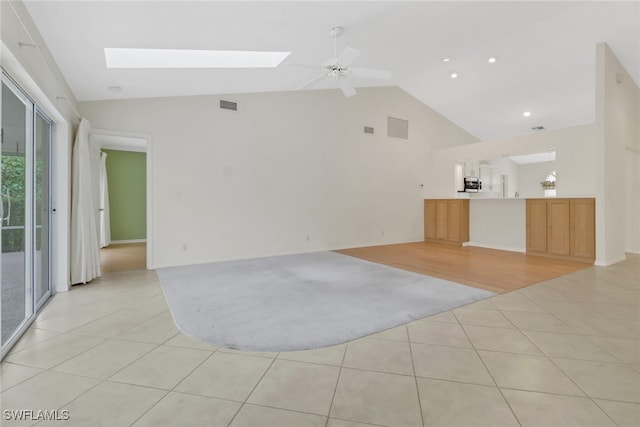 tiled empty room with lofted ceiling with skylight and ceiling fan