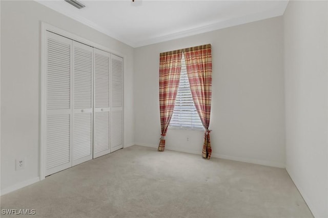 unfurnished bedroom with ornamental molding, light carpet, and a closet