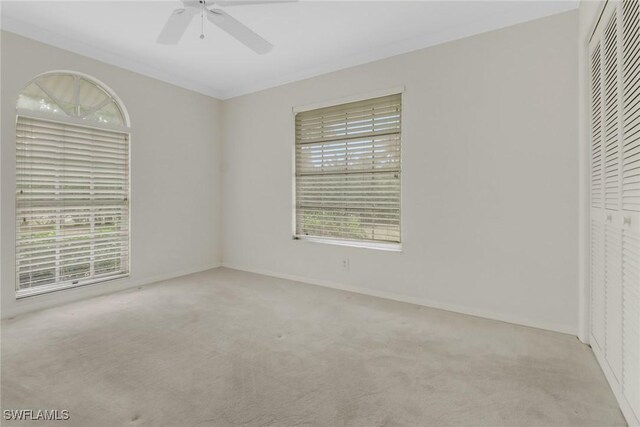 unfurnished bedroom with multiple windows, light carpet, and ceiling fan