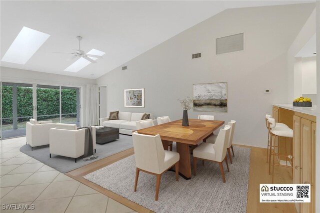 dining area featuring light tile patterned flooring, ceiling fan, a skylight, and high vaulted ceiling