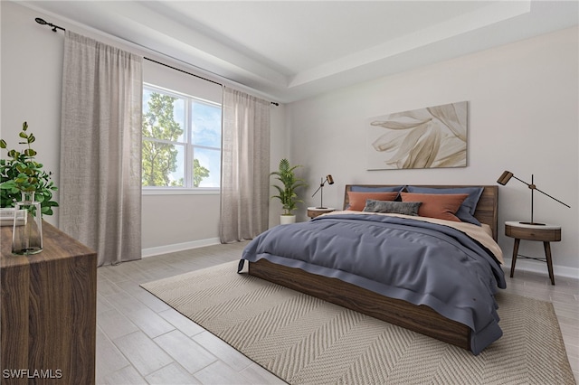 bedroom featuring light hardwood / wood-style flooring and a tray ceiling