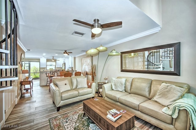 living room featuring crown molding, ceiling fan, and light wood-type flooring