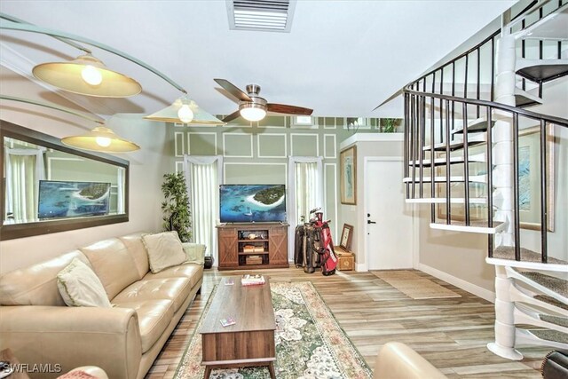 living room featuring light hardwood / wood-style flooring, ceiling fan, and a healthy amount of sunlight