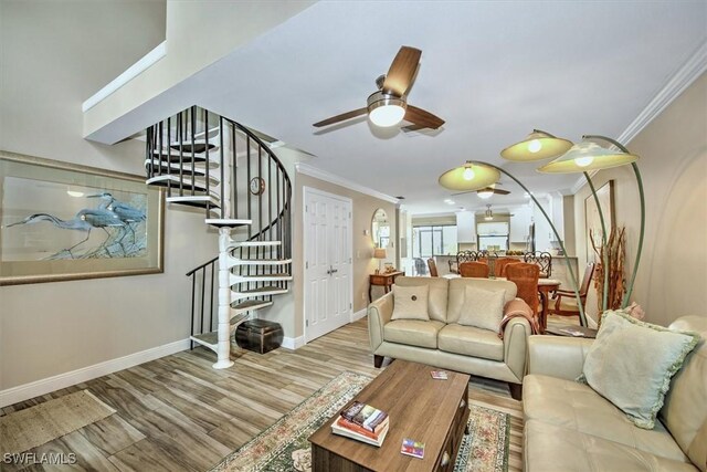 living room featuring light wood-type flooring, ornamental molding, and ceiling fan