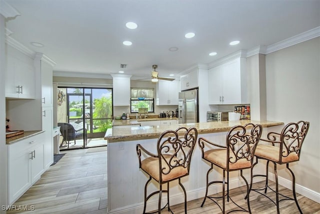 4803 SW Santa Barbara Ct Unit 2, Cape Coral, FL 33914 - kitchen featuring light wood-style floors, a peninsula, white cabinets, and stainless steel refrigerator with ice dispenser
