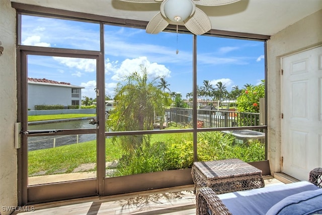 sunroom / solarium featuring a water view and ceiling fan