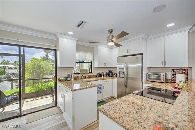 kitchen with plenty of natural light, ceiling fan, white cabinetry, and stainless steel refrigerator with ice dispenser