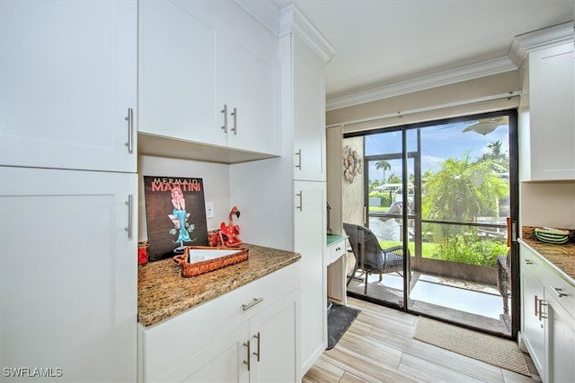 kitchen with crown molding, stone countertops, white cabinets, and light hardwood / wood-style floors