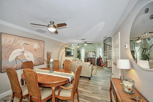 dining area with light wood-type flooring, ceiling fan, and crown molding