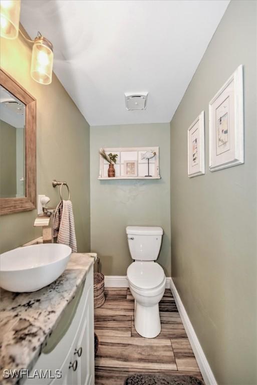 bathroom with toilet, hardwood / wood-style flooring, and vanity