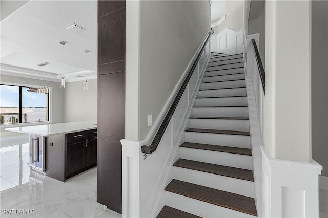 staircase with marble finish floor, a raised ceiling, and visible vents