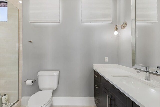 bathroom featuring tile patterned flooring, vanity, toilet, and a tile shower