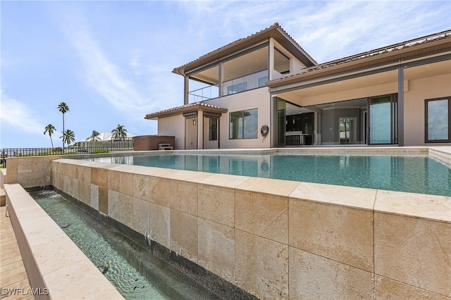 view of swimming pool with an infinity pool and fence