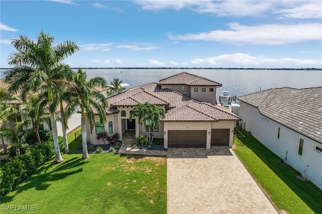 mediterranean / spanish-style house with a water view, a front yard, and a garage