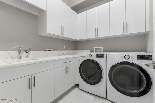 clothes washing area featuring cabinets, sink, and washing machine and clothes dryer