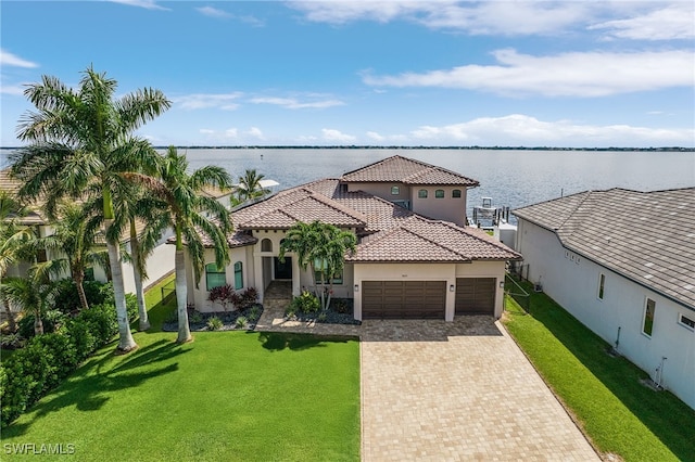 mediterranean / spanish-style house featuring a garage, a water view, and a front yard