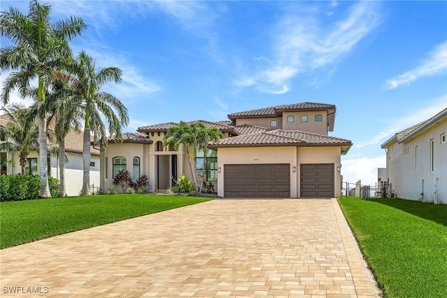 mediterranean / spanish-style home featuring a garage, stucco siding, decorative driveway, and a front yard