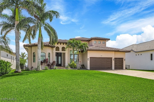 mediterranean / spanish-style home with a tile roof, stucco siding, a garage, driveway, and a front lawn